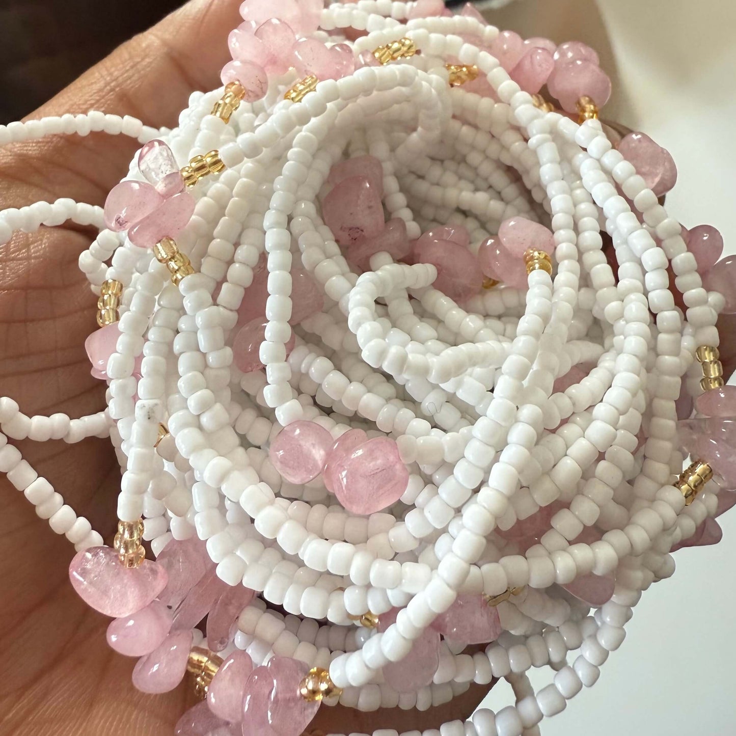 Close-up of white and pink beaded necklaces with gold accents.