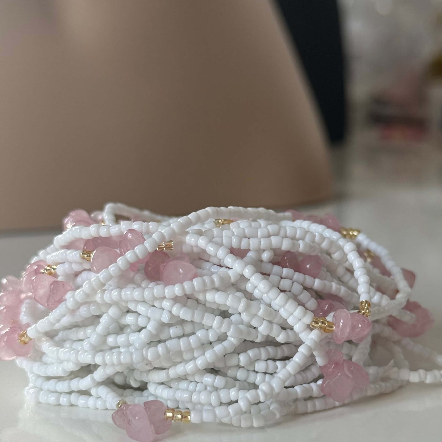 waist beads White beaded necklace with pink beads on a white surface