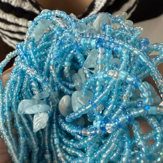 Close-up of blue beaded strings with aquamarine stones held by a person