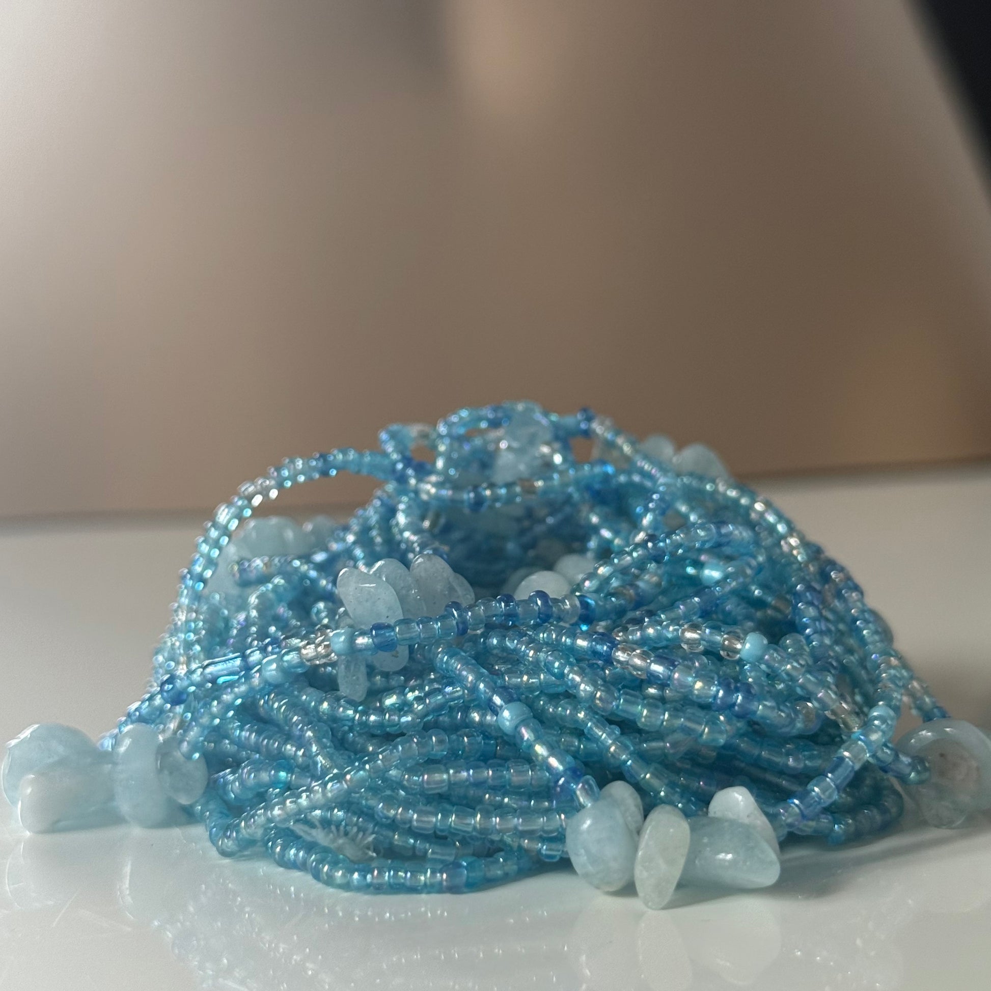 Blue beaded waist necklace with aquamarine stones on a light background