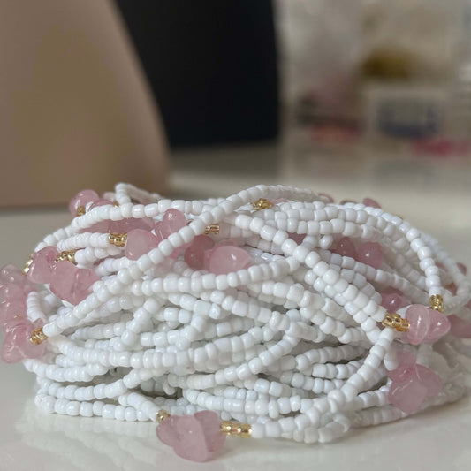 White waist beads 
with pink rose quartz stones on a white surface