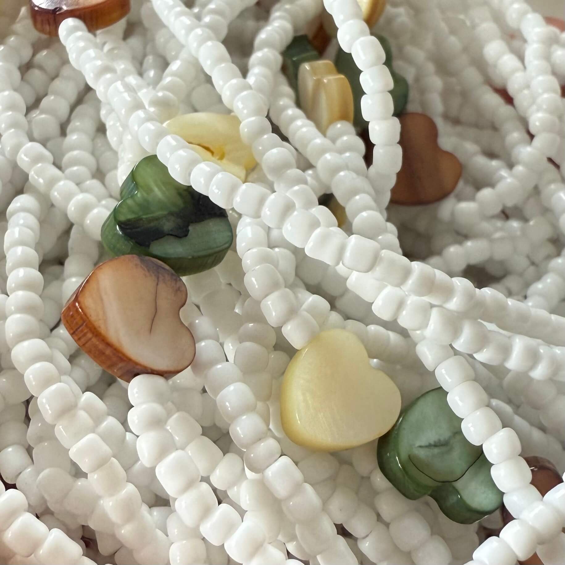 Close-up of a beaded necklace with white beads and heart-shaped colored beads.